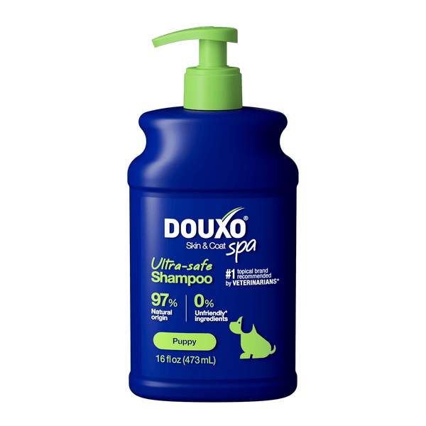 The front of a 16 fl oz bottle of DOUXO Puppy Ultra-safe Shampoo for dogs, featuring a dark blue bottle with a light green pump dispenser and green label accents.