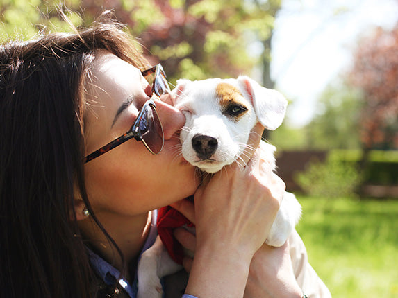 A person holding and kissing a puppy's face.